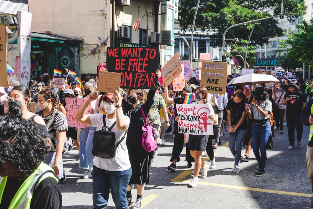 a group of people walking down a street holding signs