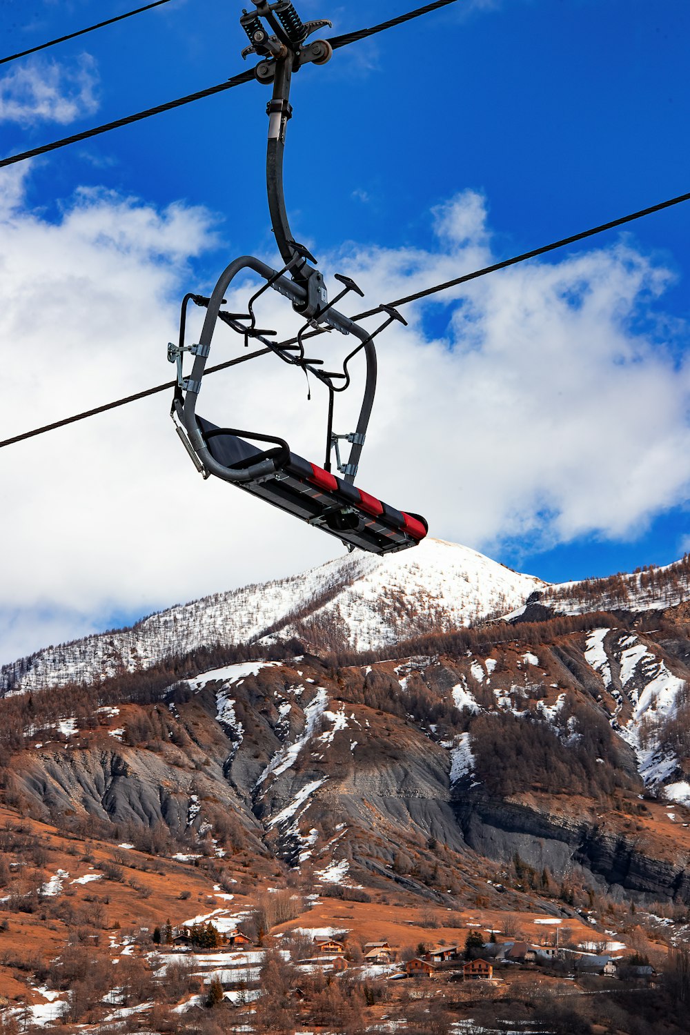 a ski lift going up a mountain with a snow covered mountain in the background
