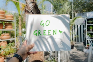 a person holding up a sign that says go green