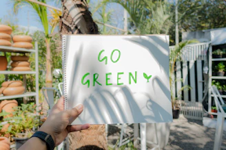 a person holding up a sign that says go green