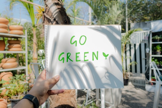 a person holding up a sign that says go green