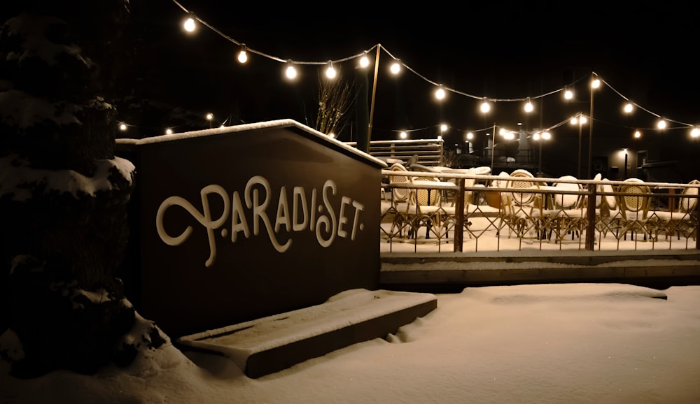 a bench covered in snow next to a fence