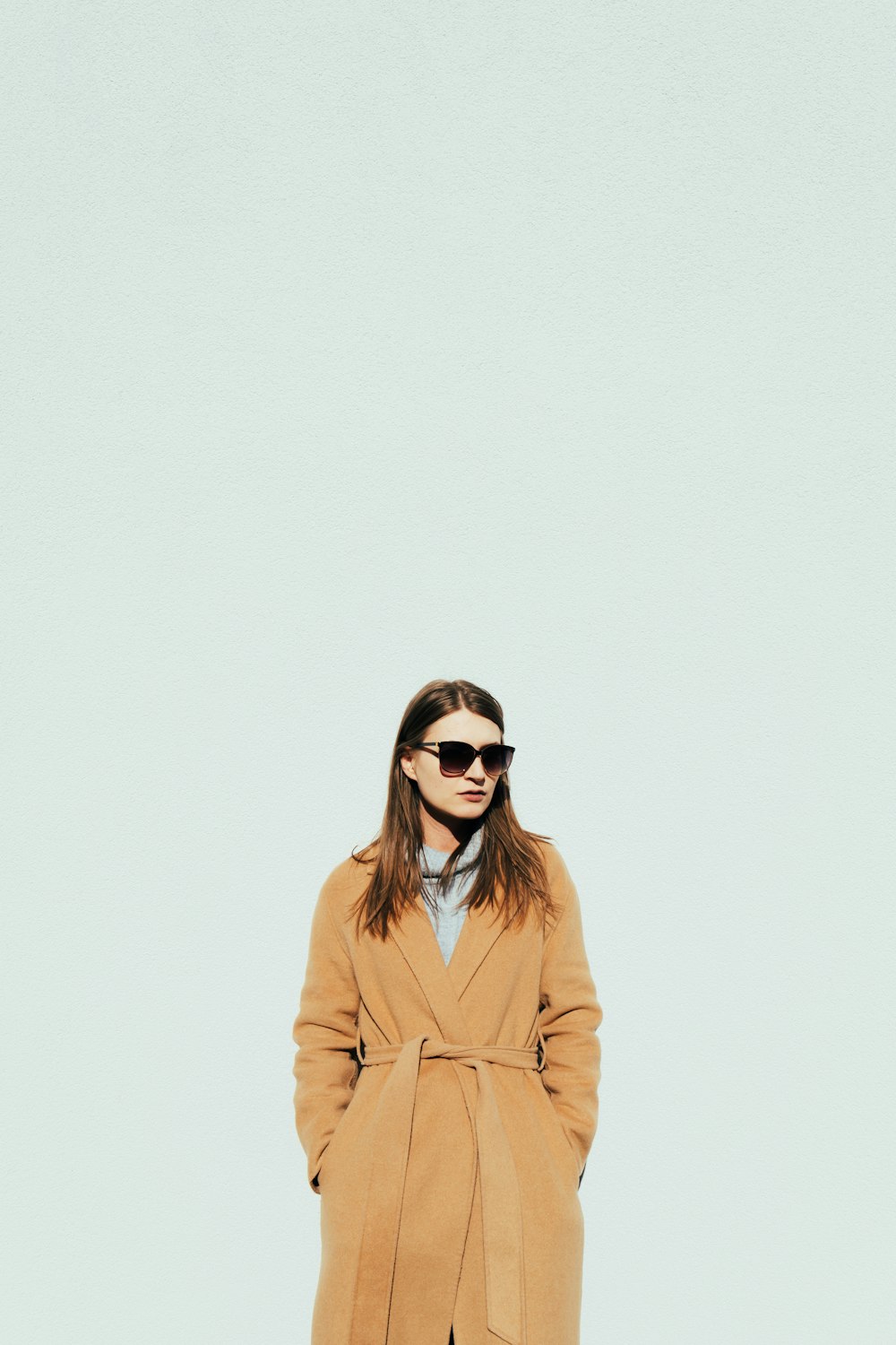 a woman in a tan coat and sunglasses
