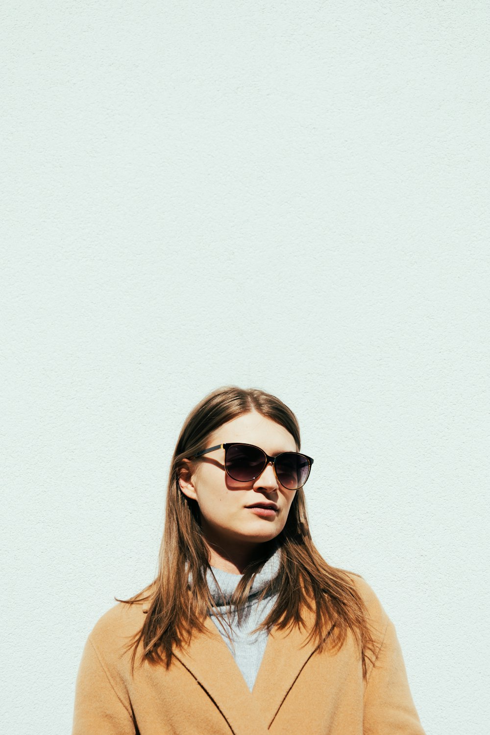 a woman wearing a tan coat and sunglasses