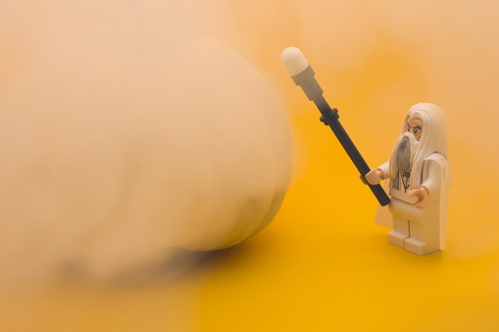 a lego figurine holding a large object on a yellow background