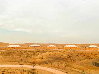 A row of well-lit accommodation portacabins surrounded by desert landscaping at dusk.
