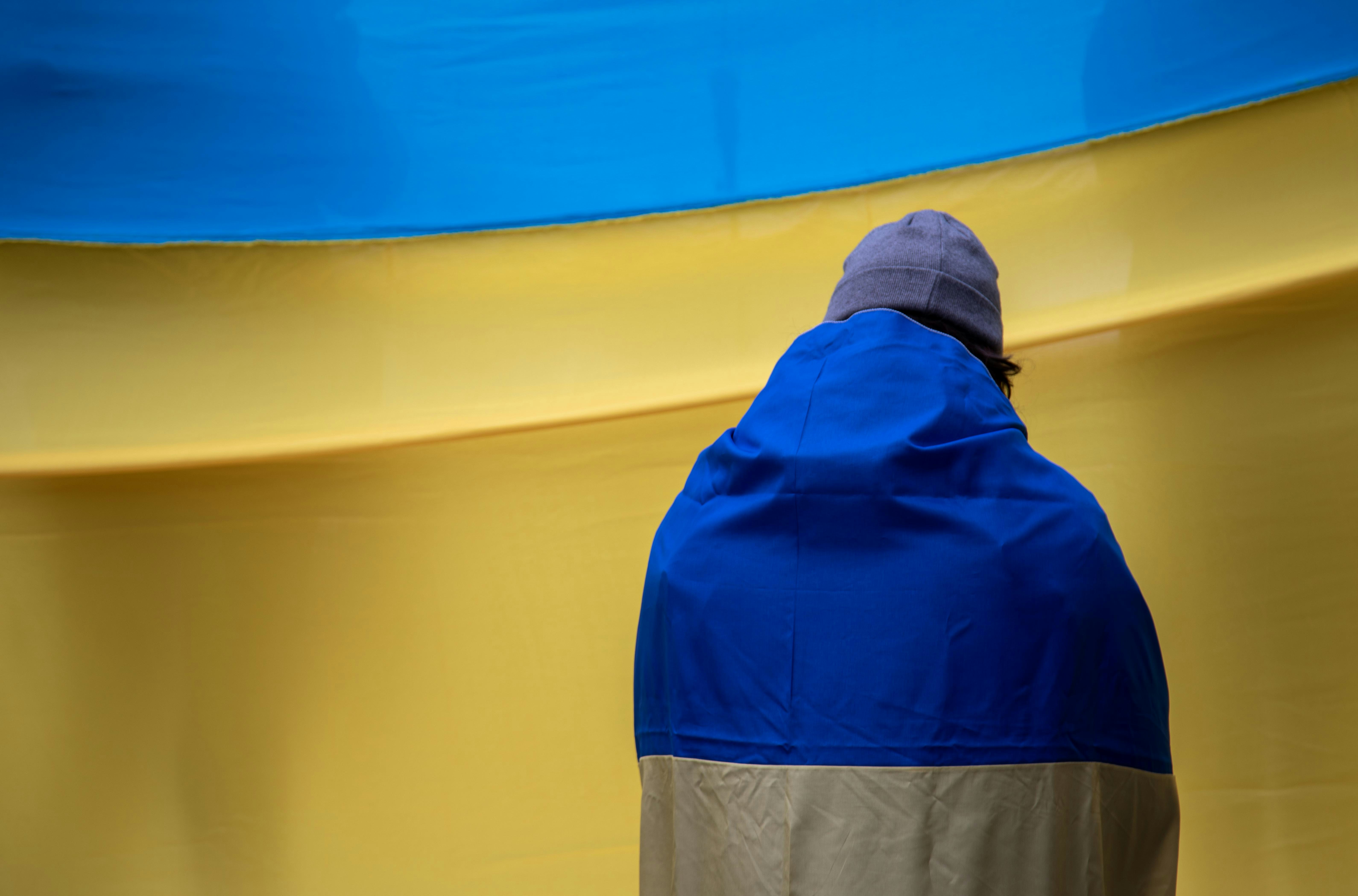 Un homme en veste bleue assis devant un gros objet bleu et jaune