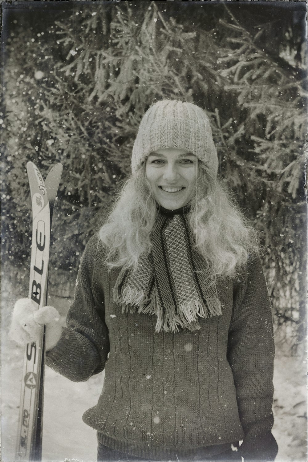 a black and white photo of a woman holding skis