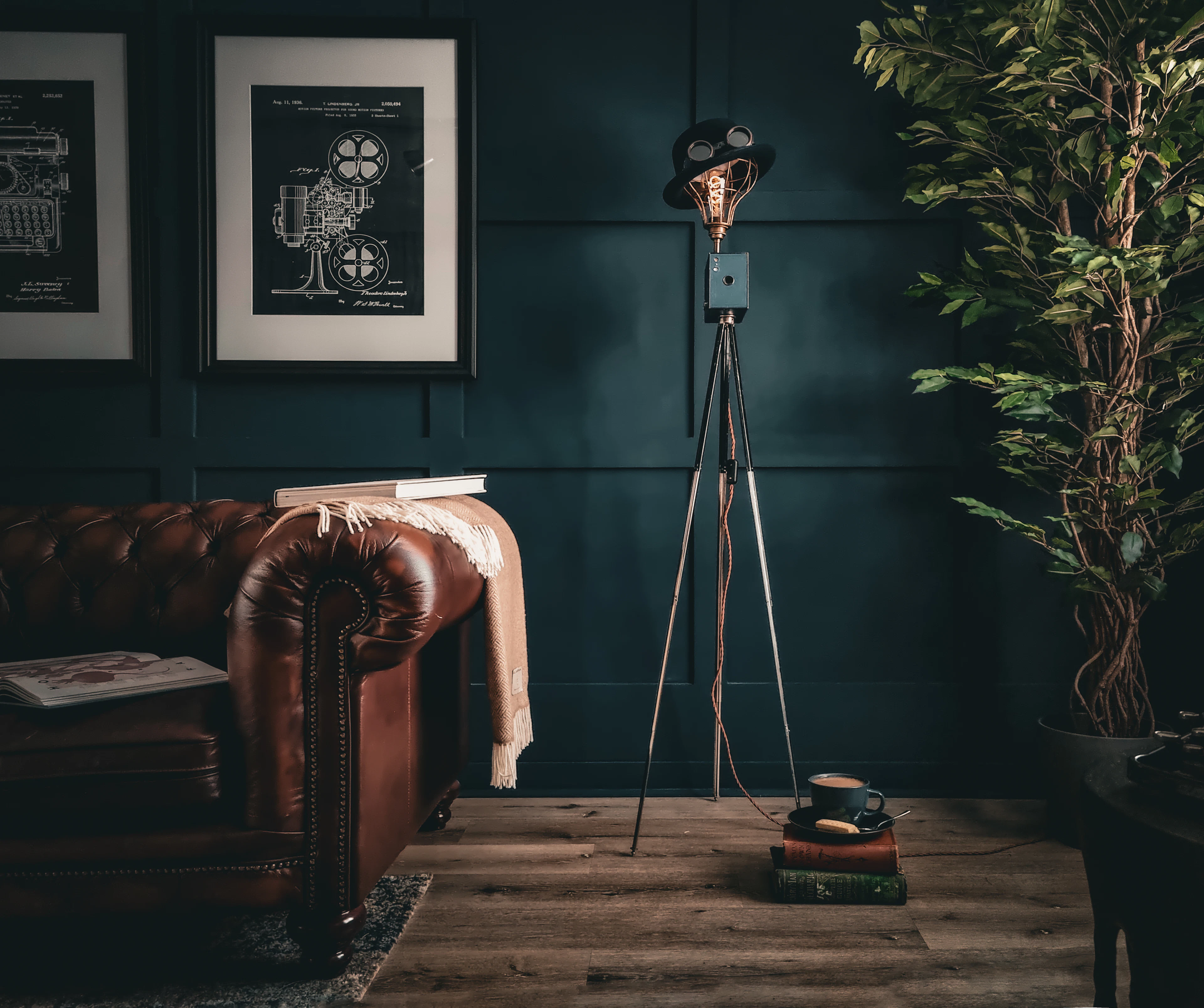A dark green living room with a leather sofa and a tripod floor lamp