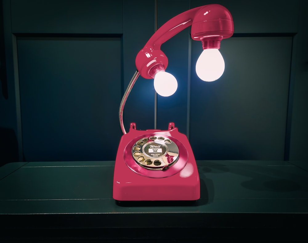 a pink telephone with two lights on it