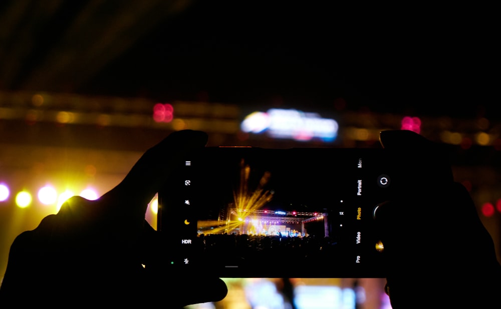 a person taking a picture with a cell phone of a concert