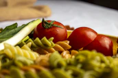 Colorful assortment of pasta shapes arranged on a vibrant cloth, ready to cook.