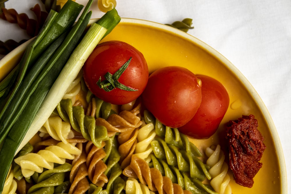 a yellow plate topped with pasta and vegetables