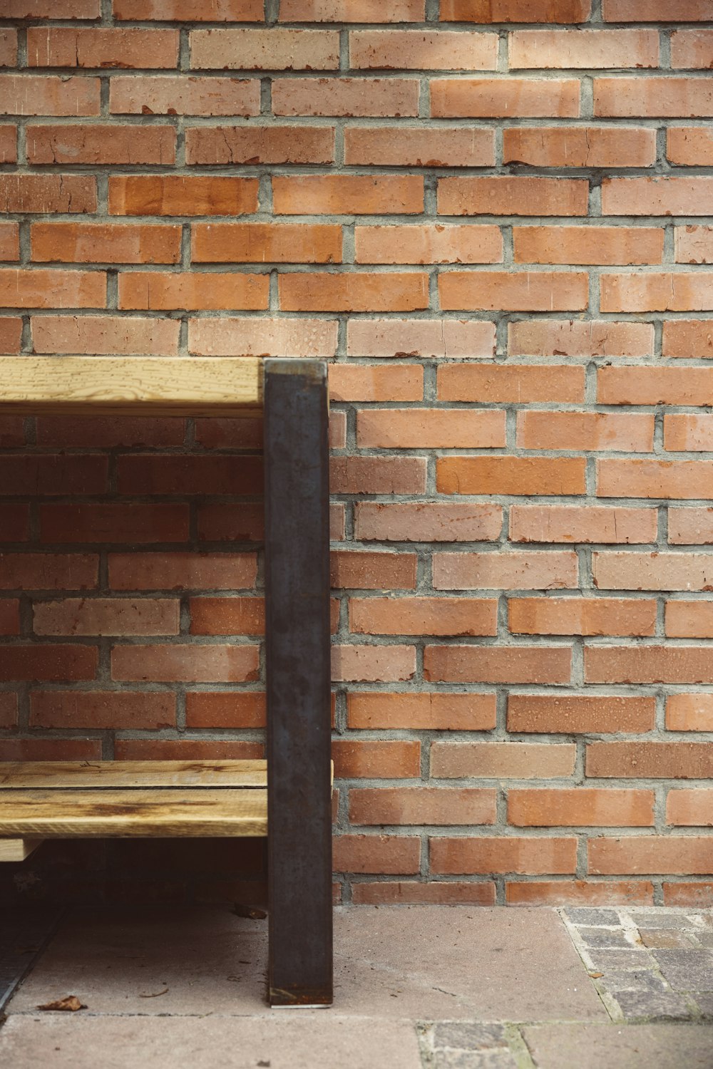 a wooden bench sitting next to a brick wall
