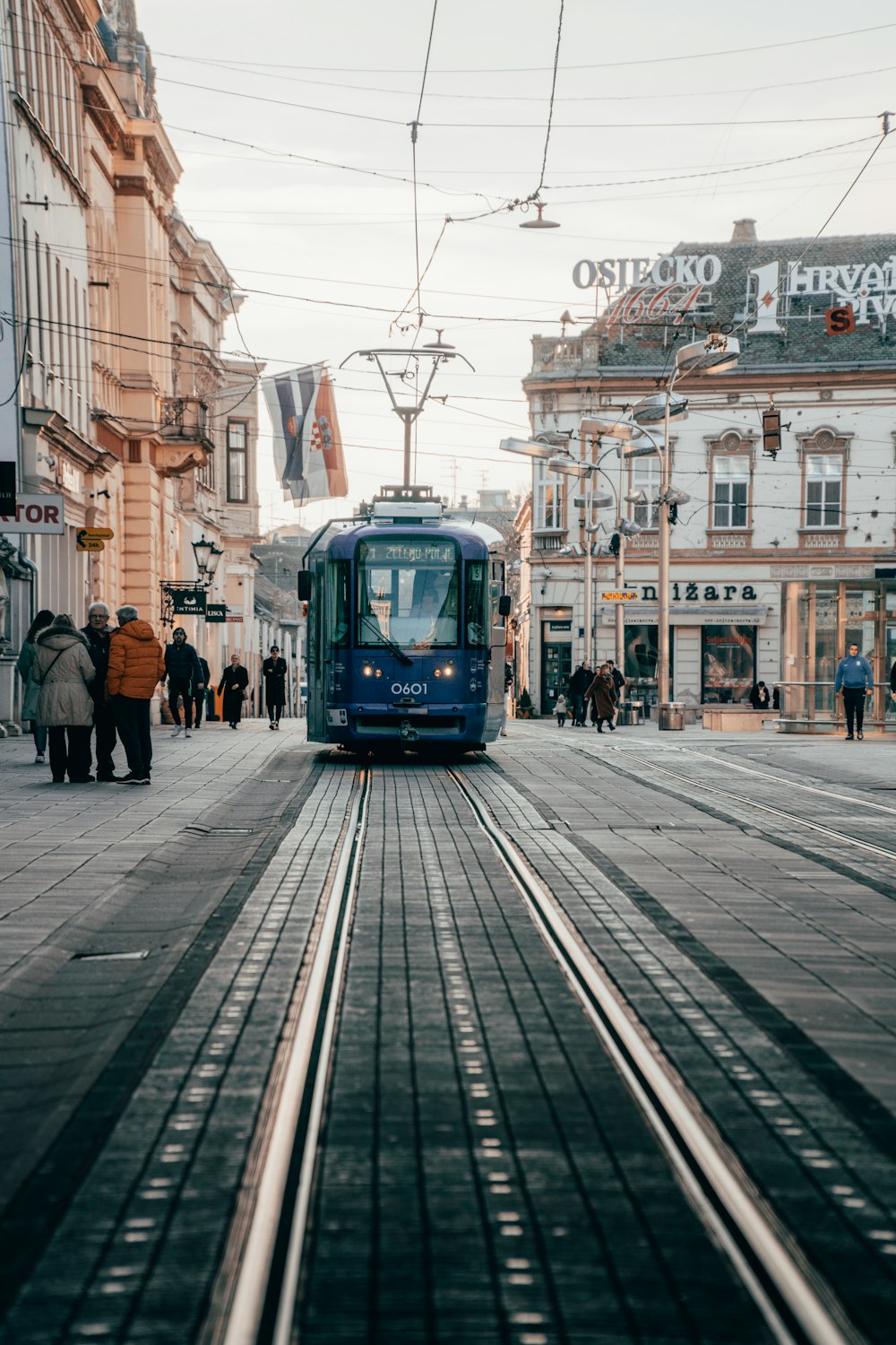 Un tren azul que viaja por una calle junto a edificios altos