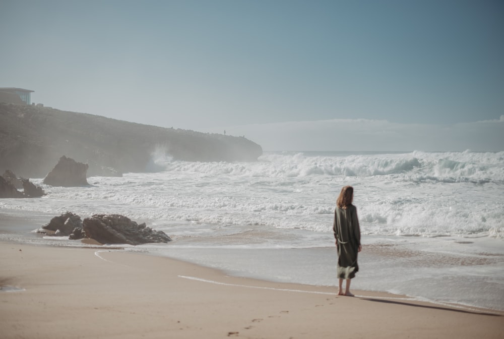 a woman standing on a beach next to the ocean