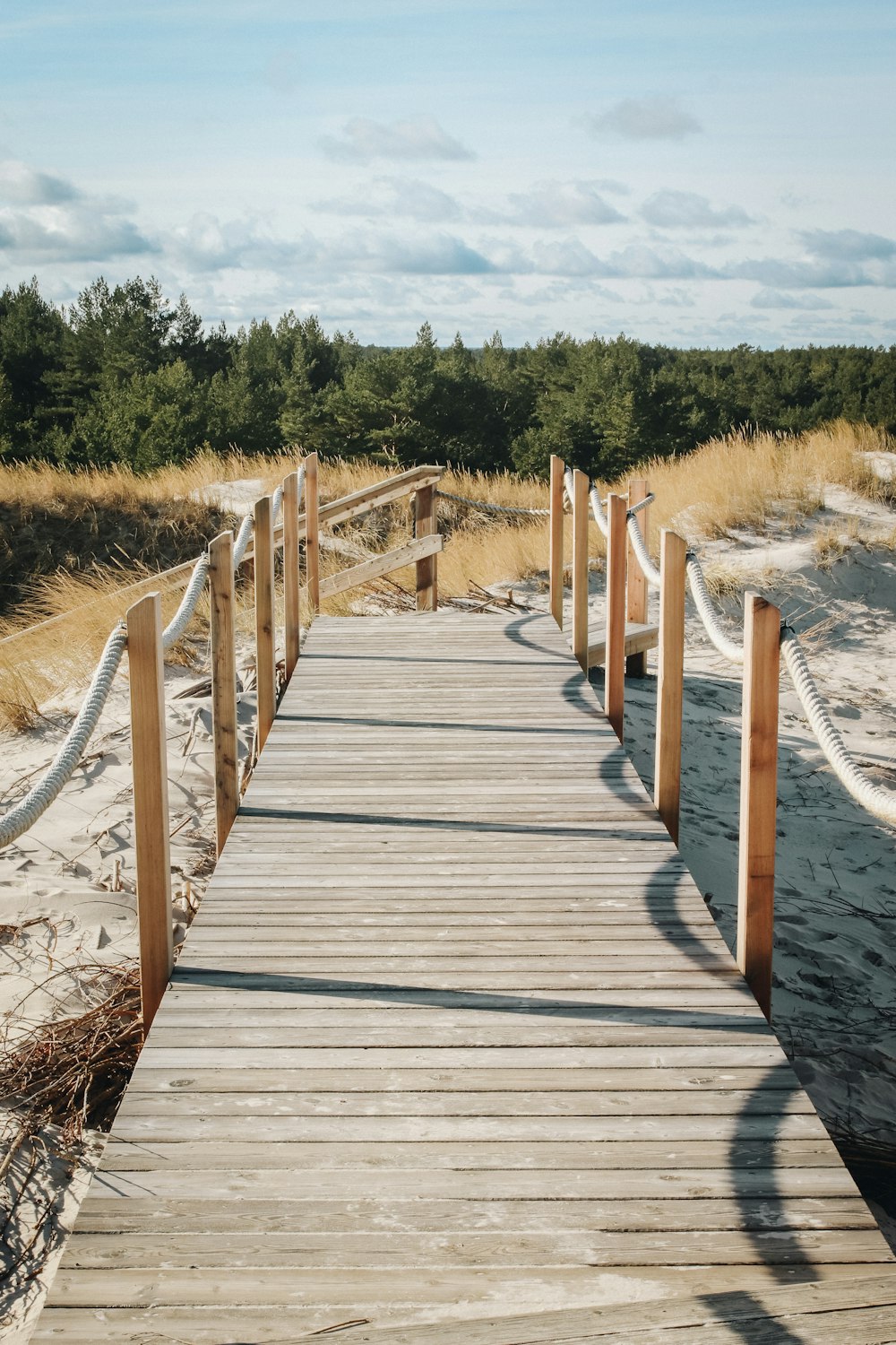 uma passarela de madeira que leva a uma praia de areia