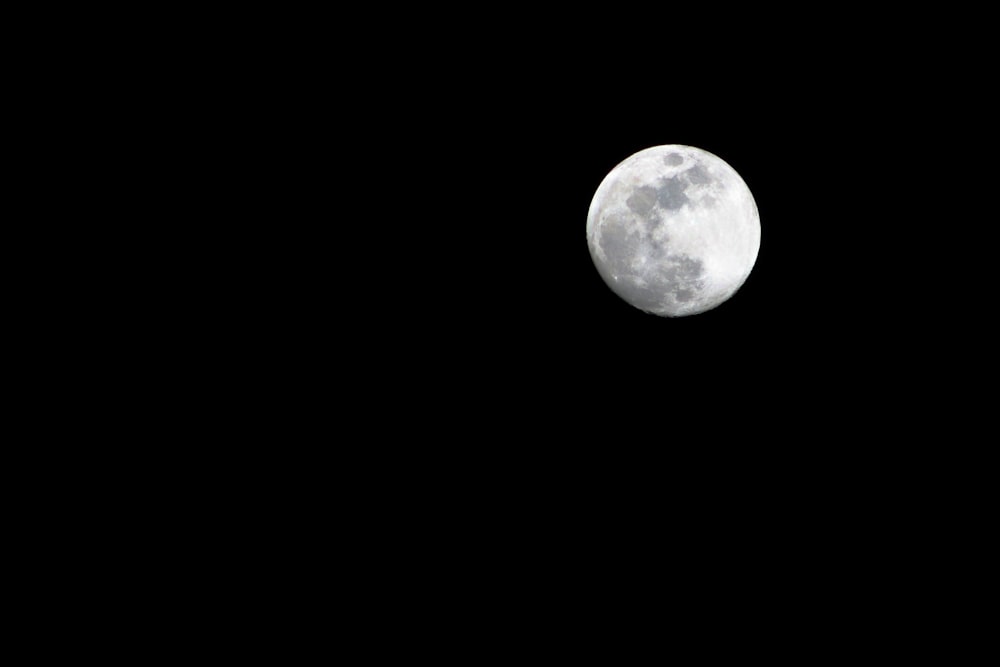 a full moon is seen in the dark sky