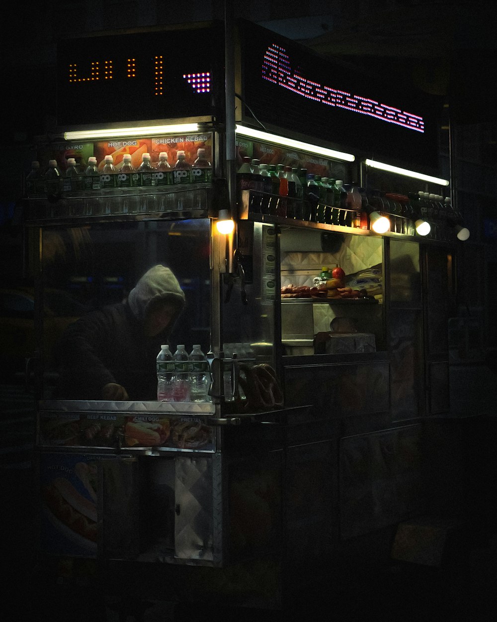 a man standing in front of a food cart at night