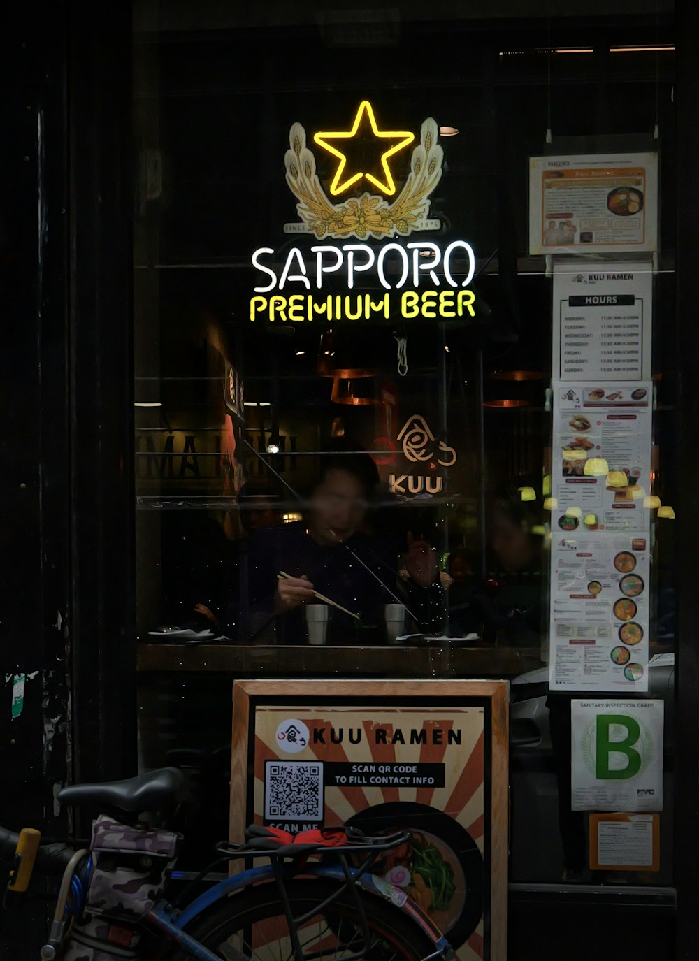 a man sitting in a restaurant window next to a bike