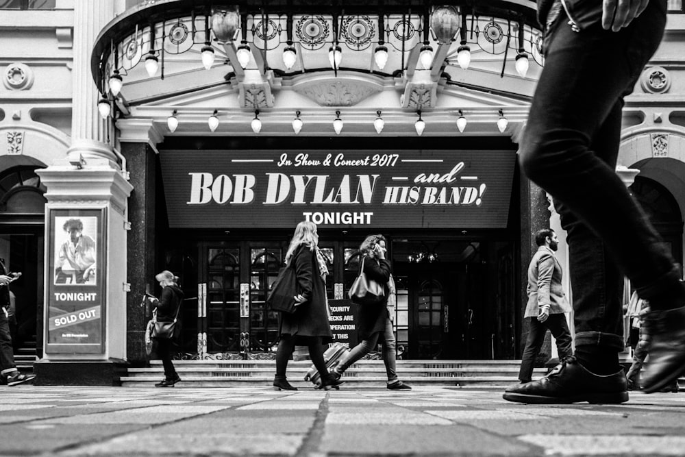 a black and white photo of people walking in front of a building