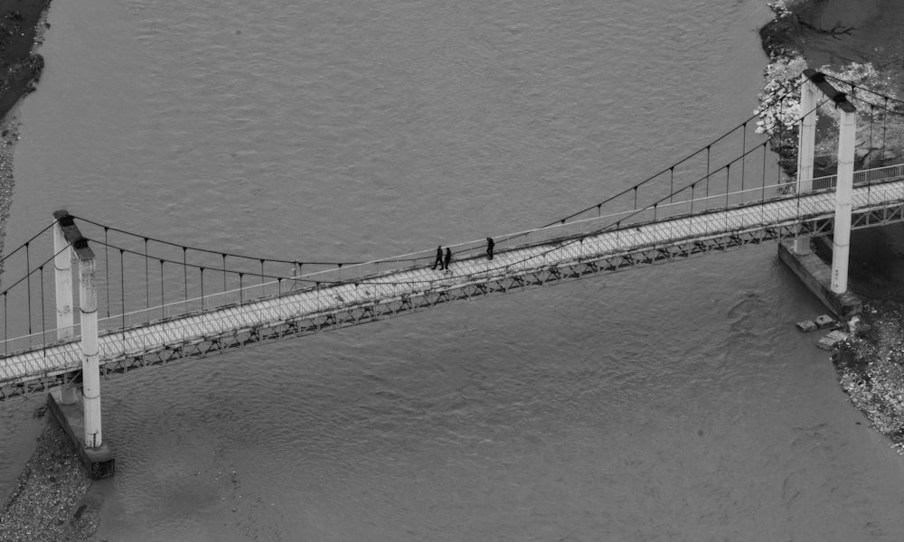 two people walking across a bridge over a river