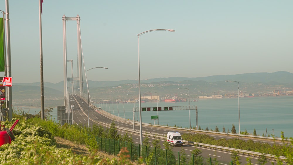 a white bus driving down a road next to a large body of water