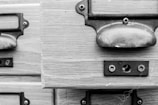 A close-up view of a vintage wooden cabinet with metal handles and a label holder. The visible wood grain and distressed metal accentuate a rustic appearance.