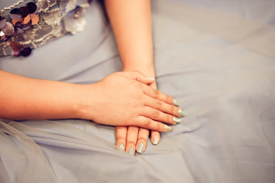 Hands with sophisticated gel manicure in soft pink tones, resting on a luxurious fabric.
