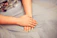 Close-up of elegant hands with glossy deep red nails resting softly on a cream silk fabric.