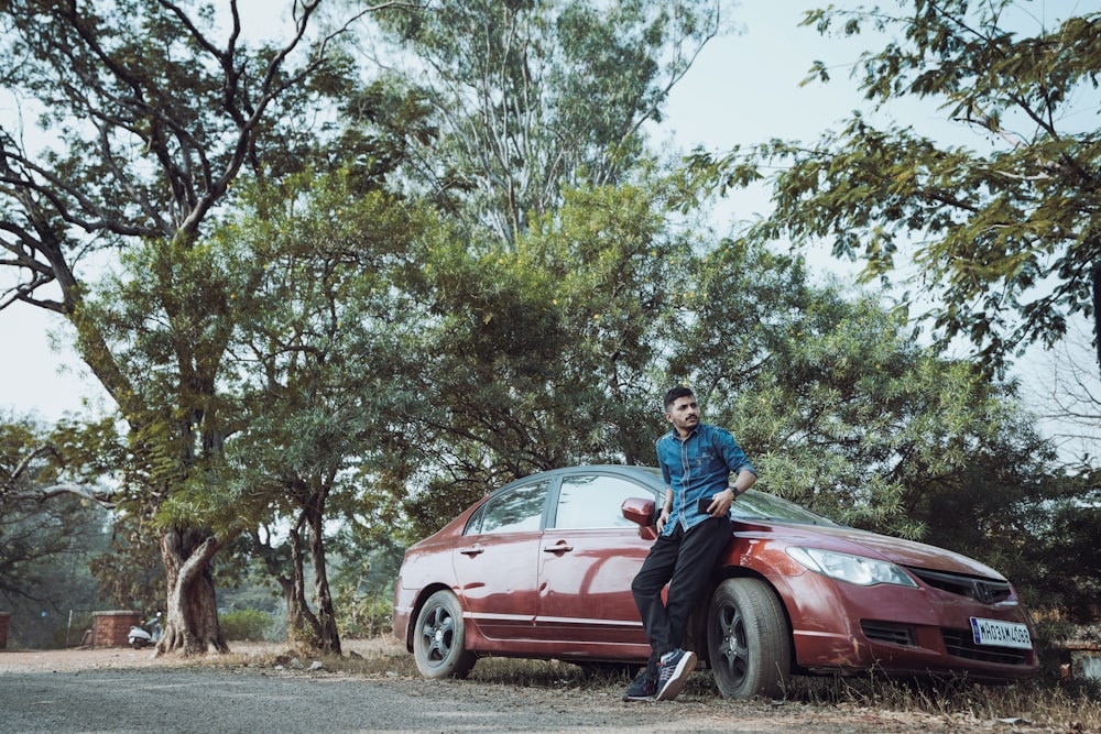 a man sitting on the hood of a red car