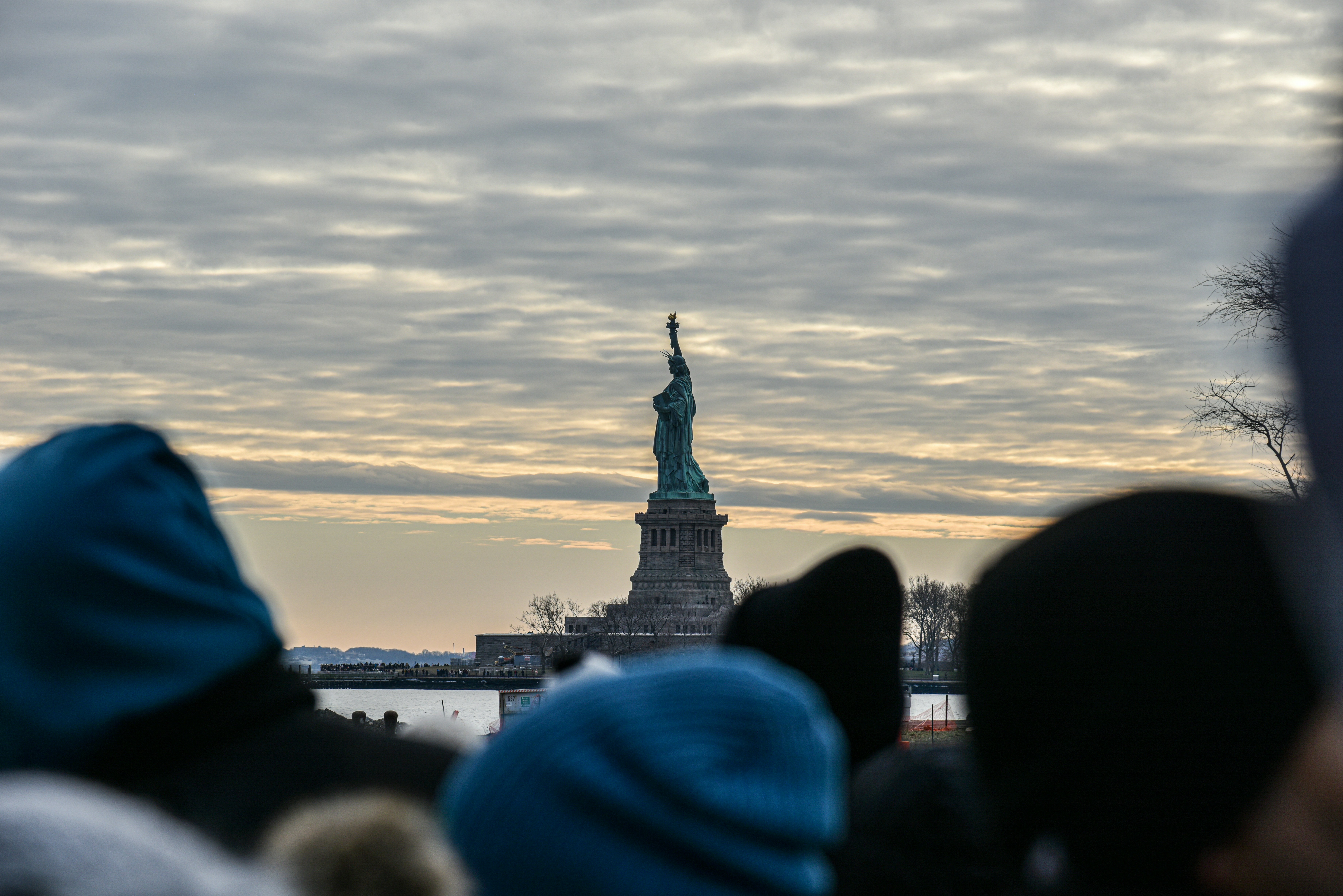 a group of people standing in front of the statue of liberty