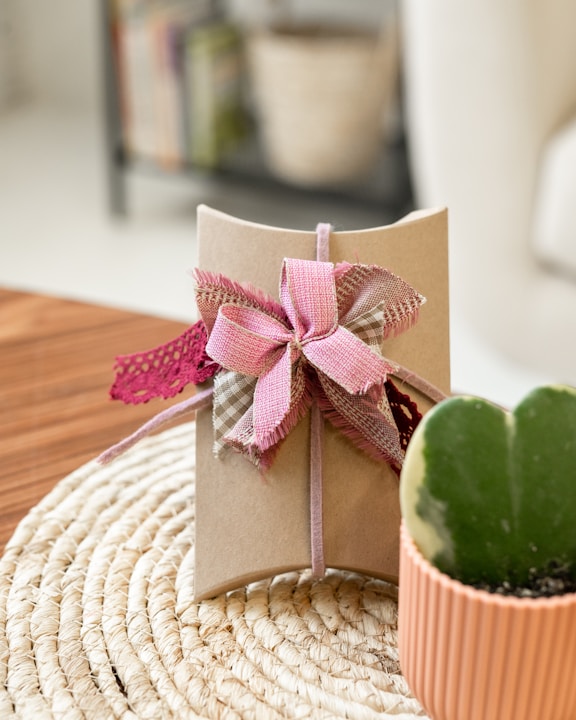 a gift wrapped in brown paper with a pink bow
