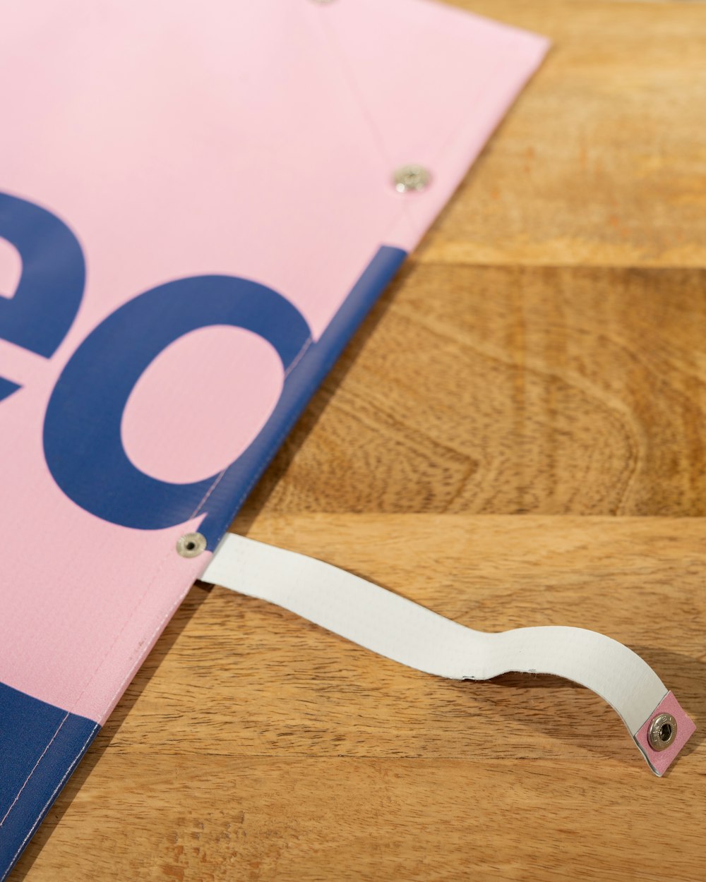 a close up of a pink and blue sign on a wooden table