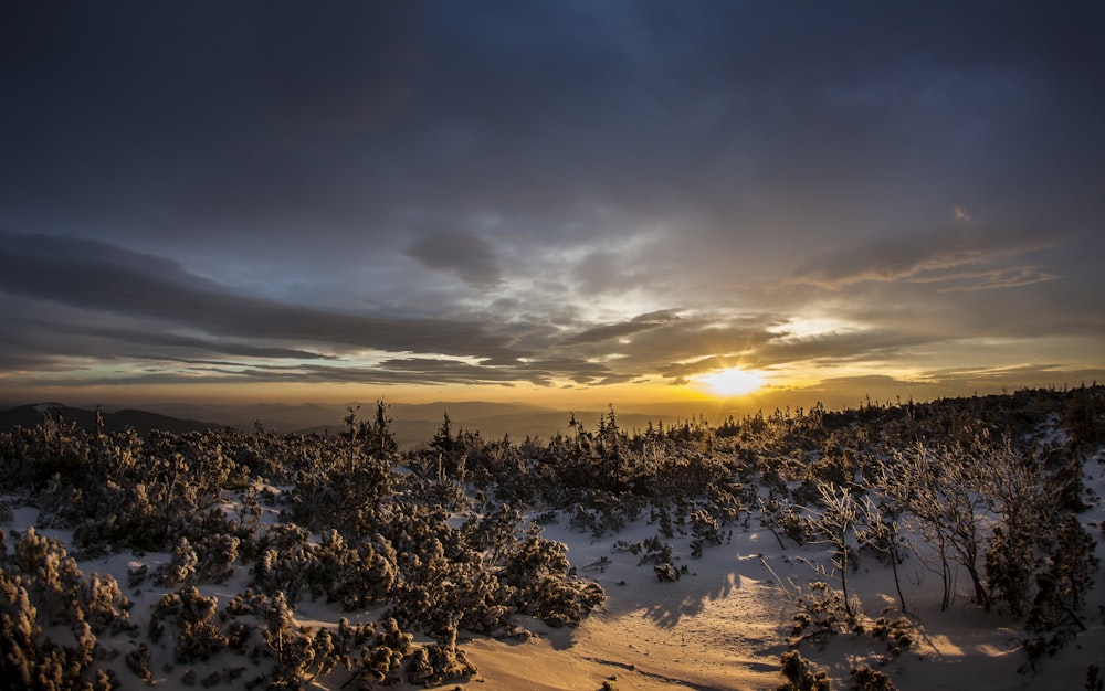 the sun is setting over a snowy mountain