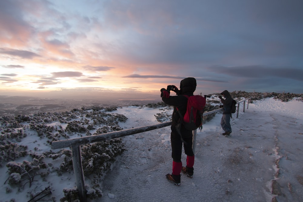 a couple of people standing on top of a snow covered slope