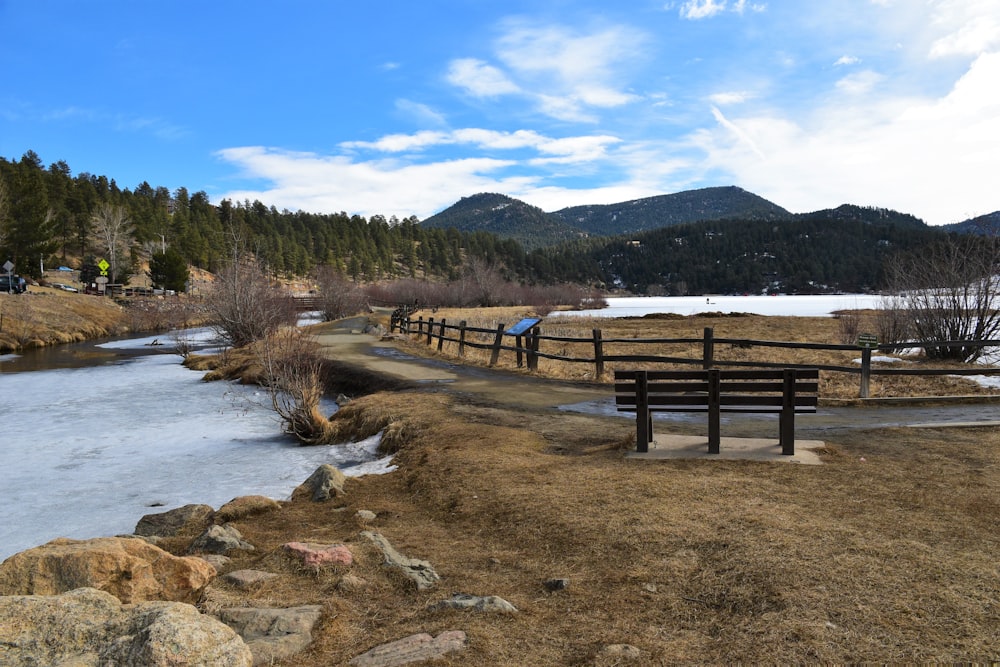 a wooden bench sitting on top of a dry grass field