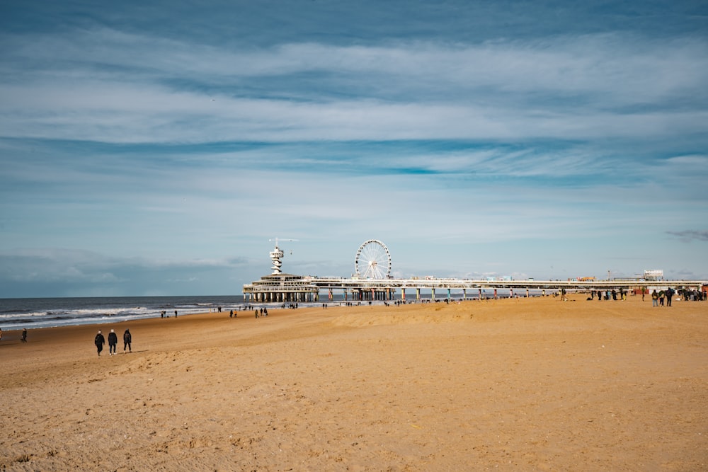 Une plage de sable avec une grande roue au loin