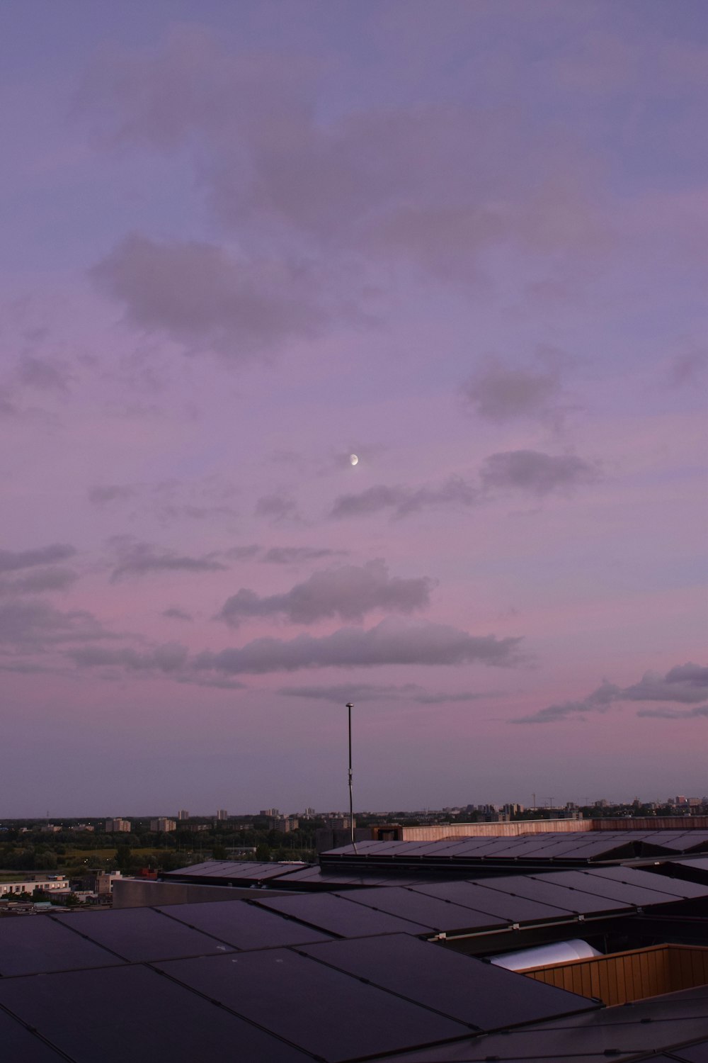 a purple sky with a half moon in the distance