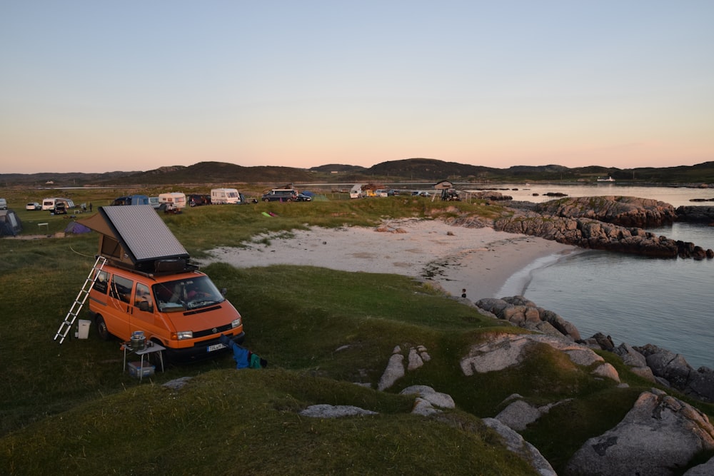 an orange van parked next to a body of water