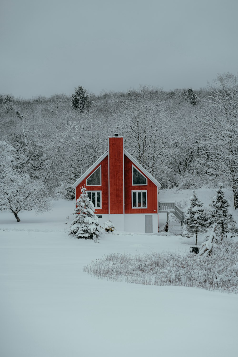 a red house in the middle of a snowy field