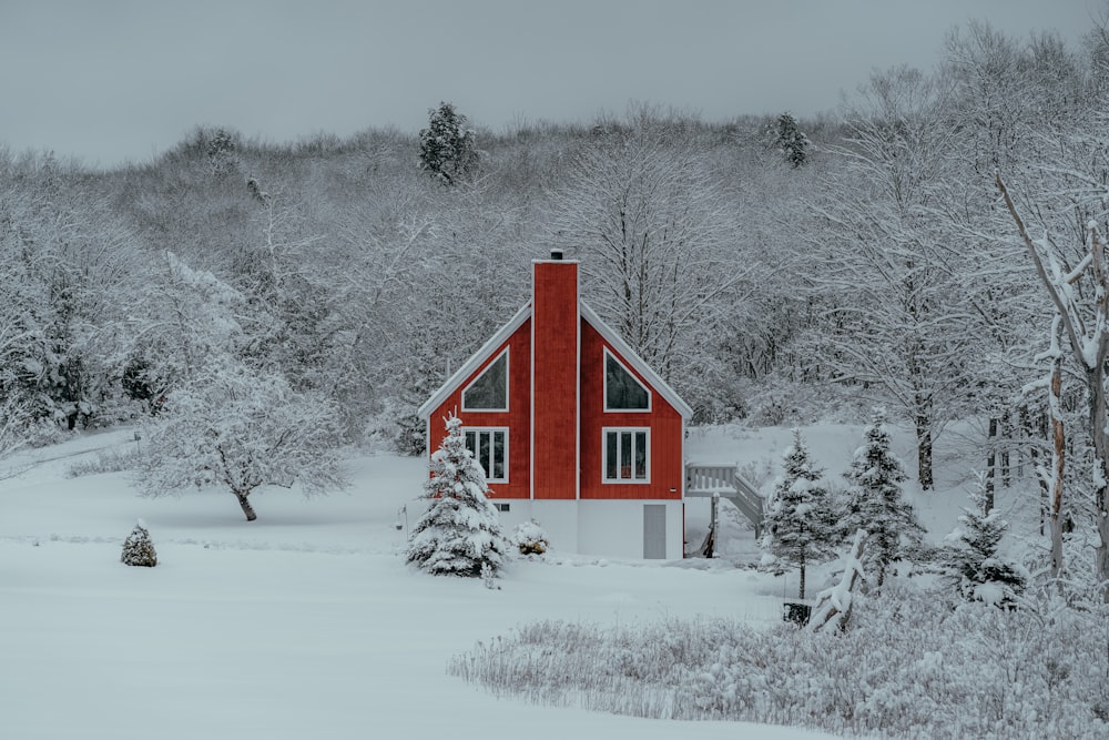 a red house in the middle of a snowy forest