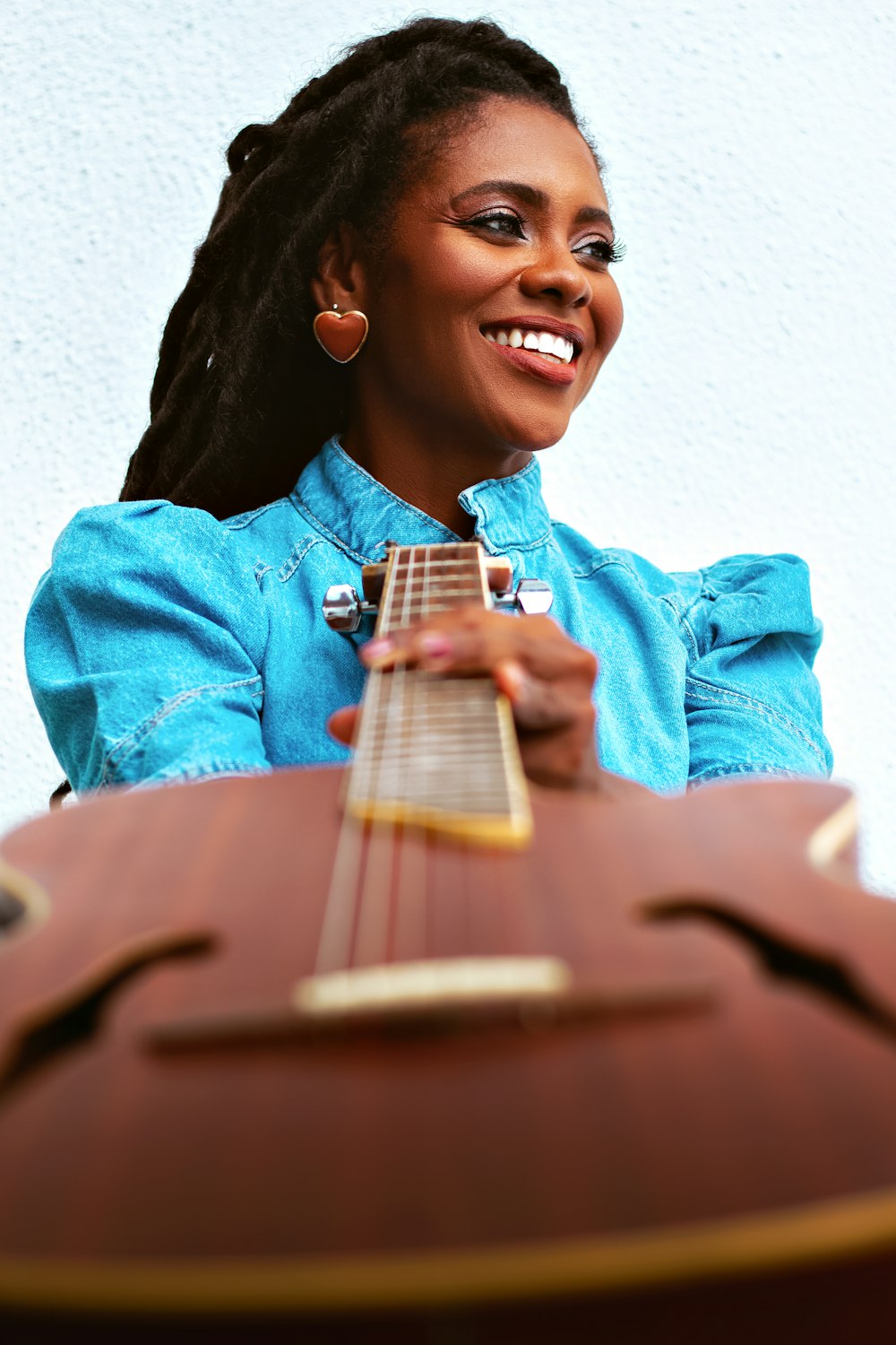 a woman smiling while holding a guitar