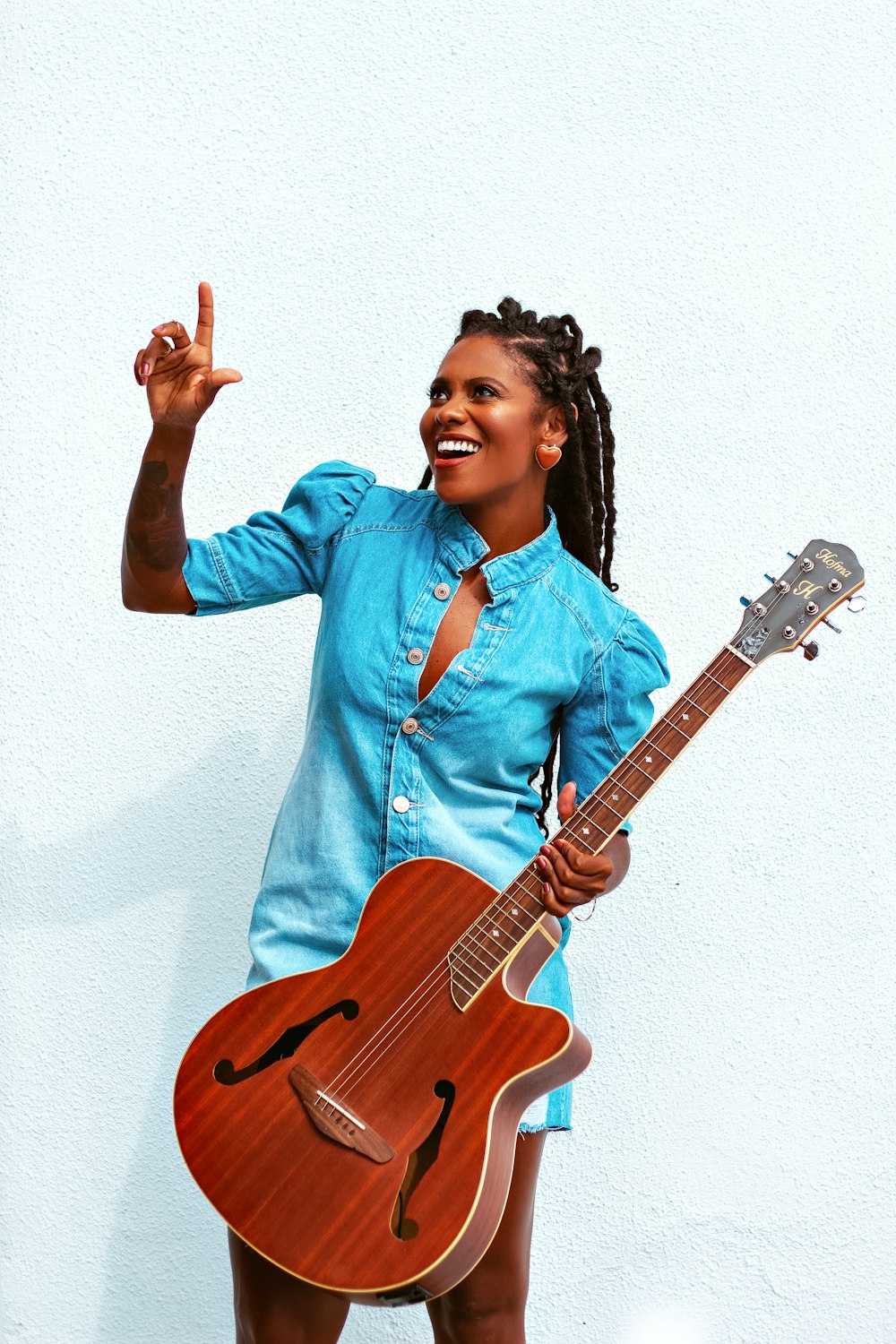 a woman in a blue shirt holding a guitar