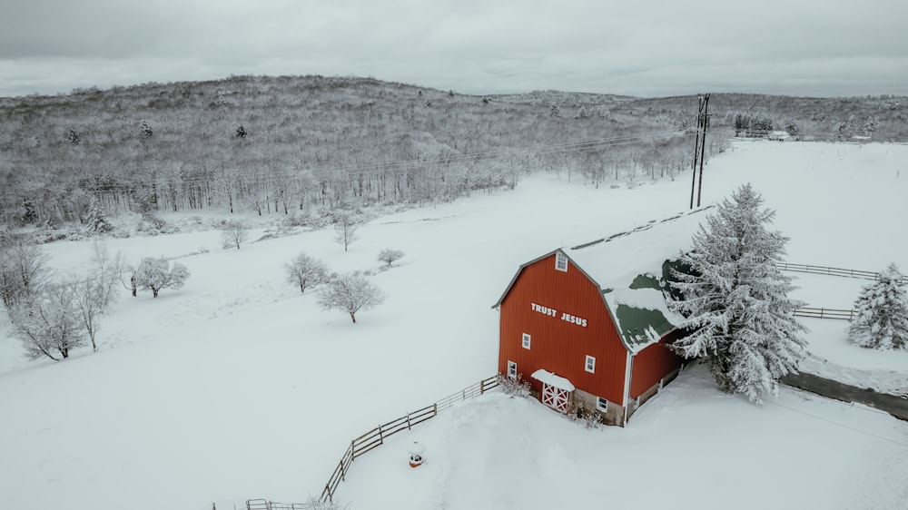 a red barn in the middle of a snowy field