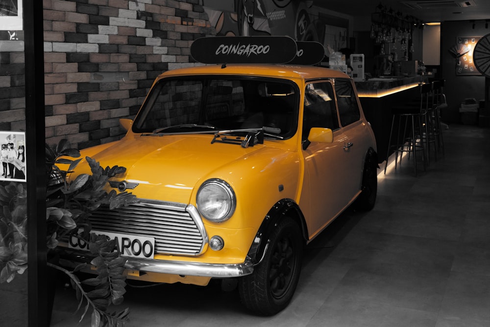 a small yellow car parked in front of a brick wall