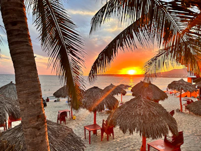 A vibrant photo of tourists enjoying a beach sunset in Bali with colorful umbrellas.