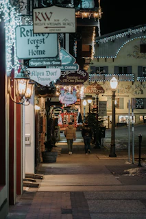 Evening view of illuminated storefronts casting a warm glow on the sidewalk, inviting evening visitors