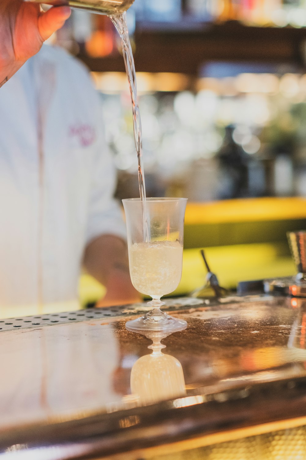 a person pouring a drink into a glass