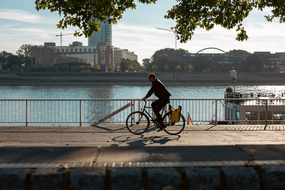 a man riding a bike down a street next to a river